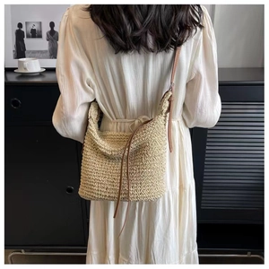 Detail of handwoven beige paper rope crossbody bag with premium brown leather strap