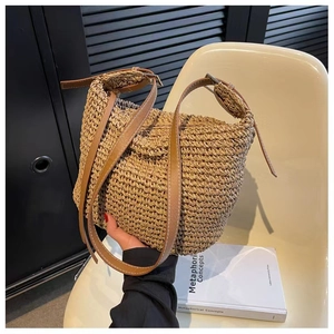 Detail of woven straw shoulder bag featuring a brown leather strap and metal buckle