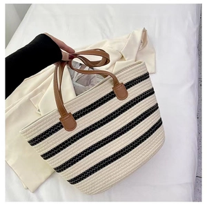 Close-up of black and white striped woven tote with premium brown leather handles