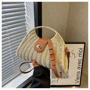 Close-up of woven straw bag with brown leather flap and golden twist lock closure