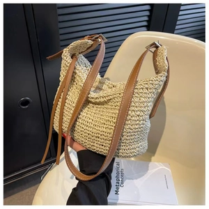 Detail of hand-woven beige straw bag with brown leather strap and buckle adjustment