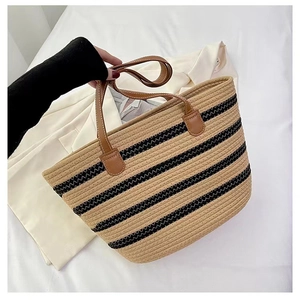 Detail of hand-woven tote bag with black wavy stripes and brown leather handles