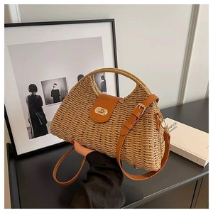 Detailed shot of straw shoulder bag with brown leather trim and golden metal twist lock