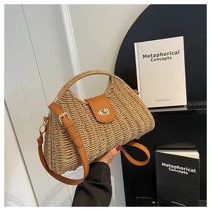 Detail view of woven straw beach bag featuring brown leather handle and gold twist lock closure