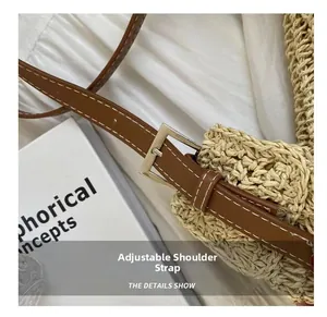 Detail of adjustable brown leather shoulder strap with silver buckle on woven straw bag