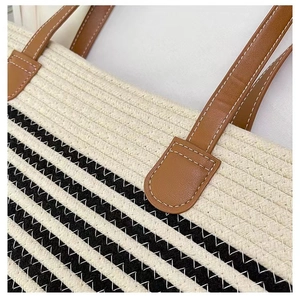 Close-up of black and white striped woven tote with brown leather handle details