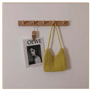 Detail shot of a yellow hand-knitted cotton rope shoulder bag hanging on a wooden hook