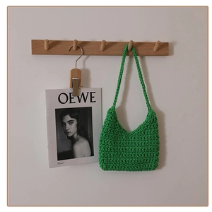 Detail of green hand-woven cotton shoulder bag showing texture and handle on a hook