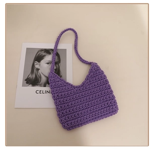 Detailed texture of purple crochet shoulder bag with minimalist woven strap on beige background