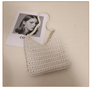 Macro detail of creamy white handmade crochet knit texture on a cotton shoulder bag