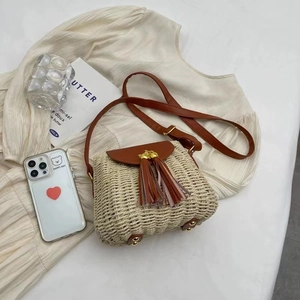 Handwoven straw crossbody bag with brown leather flap and stylish double tassels