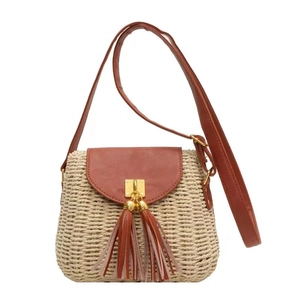 Vintage straw crossbody bag with brown leather flap and long tassels on white background