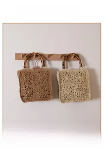 Detail of woven straw bag showing bamboo handles and hollow crochet patterns