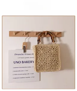 Detailed view of beige handmade woven bag with vintage bamboo handle and hollow pattern