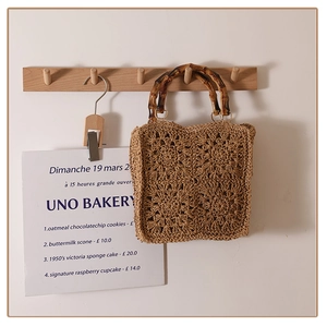 Detail of woven straw bag showing crochet floral patterns and bamboo handle texture