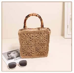 Detail of hand-woven square straw bag featuring flower pattern and bamboo handle