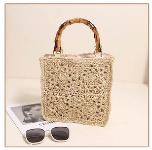 Detail of woven straw handbag featuring bamboo handles and intricate floral patterns
