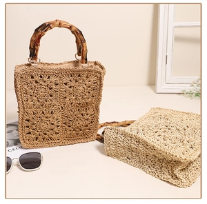 Macro shot of woven straw bag detail with bamboo handle and hollow floral pattern