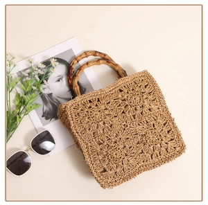 Detail of hand-woven floral pattern and natural bamboo handle on a bohemian beach bag