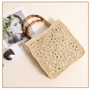 Detail of hand-woven straw bag featuring hollow floral patterns and natural bamboo handles