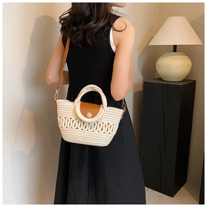 Detail of woven beach bag with pearl buckle and brown leather strap on model