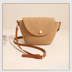 Detail of hand-woven crossbody bag featuring a large pearl clasp and brown leather strap