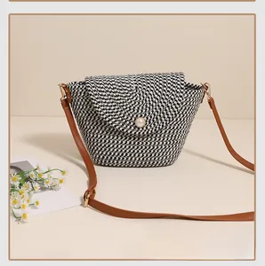 Close-up of woven straw crossbody bag with pearl buckle and houndstooth pattern texture