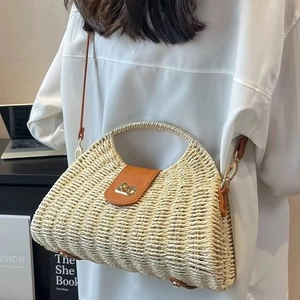 Minimalist woven straw crossbody bag with brown leather handles for seaside beach vacations
