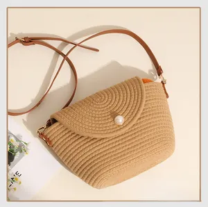 Close-up of woven straw crossbody bag featuring a large pearl button and leather strap