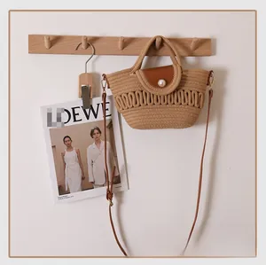 Detailed shot of woven cotton shoulder bag with leather flap and pearl buckle detail