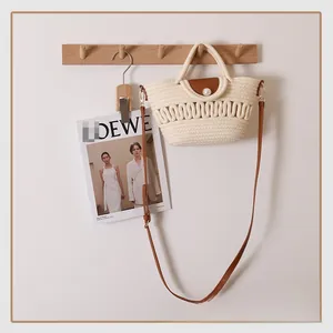 Detail of woven straw bag with brown leather flap and large pearl closure ornament