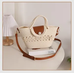 Detail of woven beach bag with brown leather flap, pearl closure and shoulder strap
