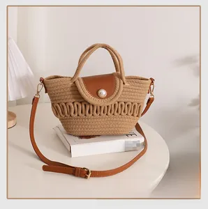 Detail of hollow woven bag with brown leather flap and large pearl accent on table