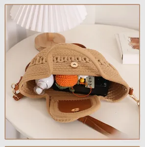 Detail of hand-woven straw crossbody bag with brown leather trim and golden metal clasp