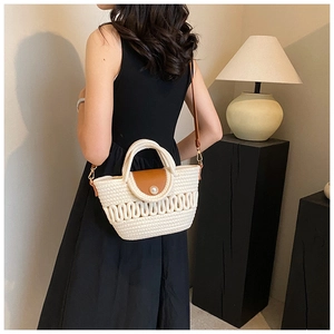 Detail of woven crossbody bag with brown leather flap and elegant pearl closure