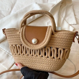 Detail of woven beach bag featuring brown leather flap and large pearl decorative clasp