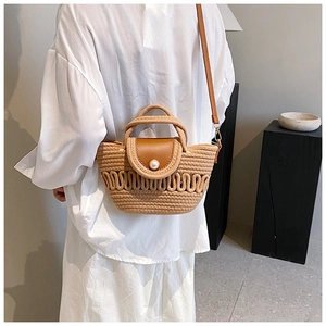 Detail of woven straw handbag with brown leather flap and elegant pearl decoration