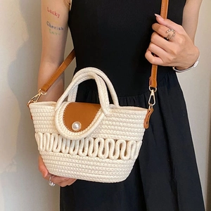 Close-up of woven crossbody bag with a brown leather flap and a large pearl button detail