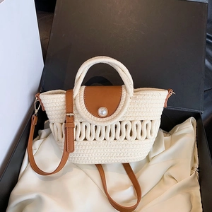 Detailed shot of hollow woven bag with leather flap and large pearl button in a gift box