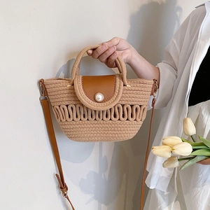 Close-up of woven straw handbag with brown leather flap and a large white pearl fastener