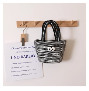 Detail of cute woven cotton handbag with quirky big eyes design hanging on a hook