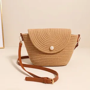 Minimalist woven straw crossbody bag with pearl button and brown leather strap