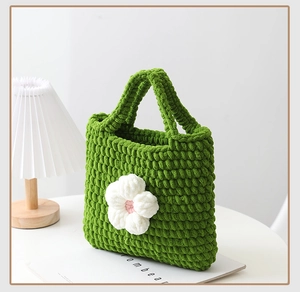 Dettaglio della borsa tote verde lavorata a mano con delicati fiori all'uncinetto in 3D