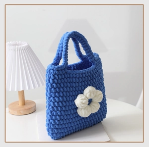 Dettaglio macro di borsa fatta a mano in ciniglia blu reale con fiore bianco decorativo