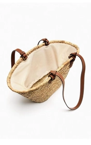 Detail view of woven straw tote with brown leather straps and spacious fabric lining interior
