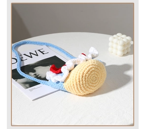Detail of handmade crochet crossbody bag with cake design and blue yarn texture