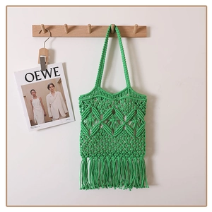 Close-up of green cotton rope woven shoulder bag with hollow mesh and long fringe tassels