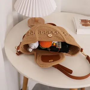 Chic woven straw crossbody bag with brown leather strap and magnetic closure on table