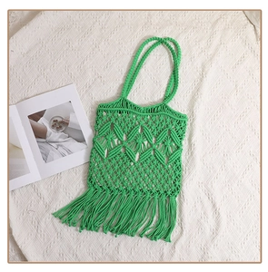 Detail of green handmade woven cotton bag with hollow diamond patterns and long tassels