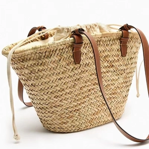 Minimalist straw tote bag with brown leather straps and drawstring liner for beach vacations